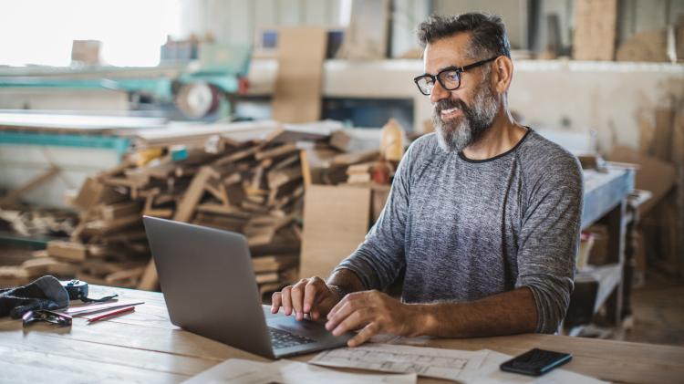 man working on laptop in a workshop