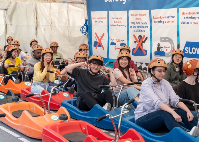 A group of students on a circus ride. The male student in the middle is giving the peace sign with his fingers.