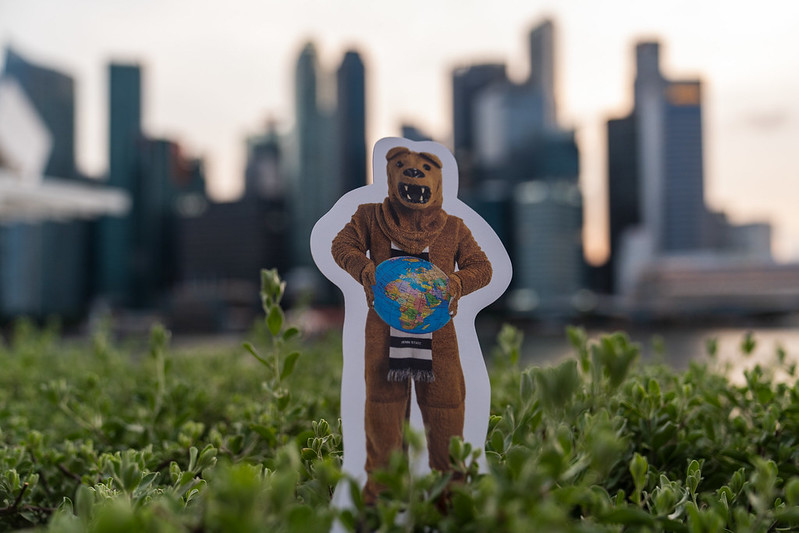 A cardboard cutout of the Nittany Lion mascot in front of the Singapore skyline